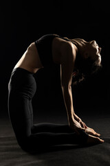 Art silhouette of a young woman doing yoga exercise. Yoga pose on black background.