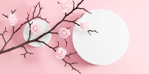 Obraz na płótnie Canvas White round podium pedestal cosmetic beauty product goods branding design presentation empty mockup on light pink background with shadows and beautiful pink flowers top view flat lay cosmetic mockup