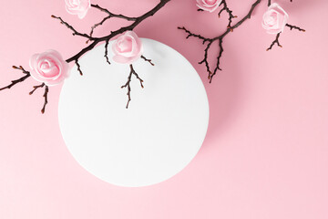 White round podium pedestal cosmetic beauty product goods branding design presentation empty mockup on light pink background with shadows and beautiful pink flowers top view flat lay cosmetic mockup