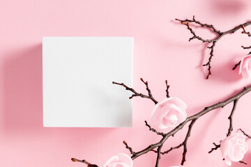 White square podium mockup pedestal cosmetic beauty product goods branding design presentation empty mockup on light pink background with shadows and beautiful pink flowers top view flat lay 