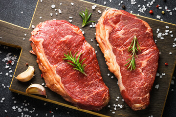 Beef steak with spices. Raw beef meat at black. Top view image.