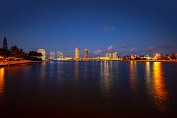 Fototapeta na wymiar Miami city skyline panorama at night skyscrapers and bridge over sea with reflection