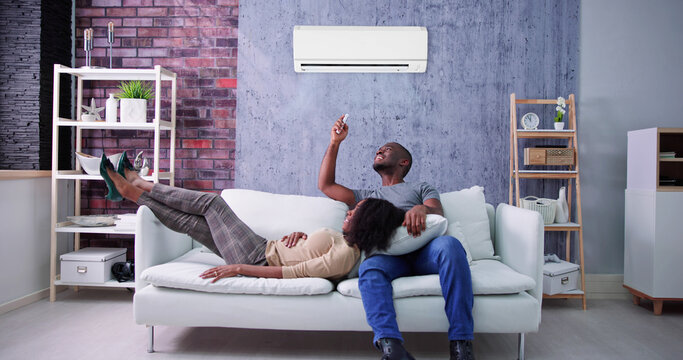 Happy Family Couple Using Air Conditioner