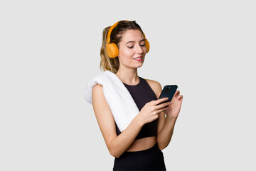 Naklejka premium Young sportswoman listening to music, motivated and focused, holding phone