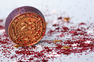 Greeting card for the Defender of the Fatherland Day. The inscription is in Russian. White, gold, red stars, an iron medal with the date February 23 on a blue background. The holiday is February 23.