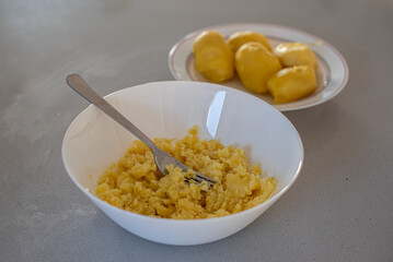 Puré de patata triturado con un tenedor en un bol. 5 patatas hervidas sin piel. Concepto de preparación de recetas en casa. Papas cocidas