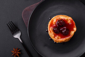 Delicious fresh pancakes with berry jam on a black ceramic plate