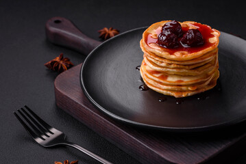 Delicious fresh pancakes with berry jam on a black ceramic plate
