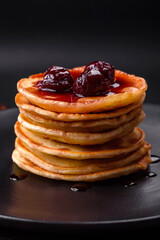 Delicious fresh pancakes with berry jam on a black ceramic plate