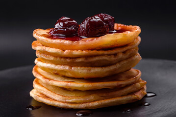 Delicious fresh pancakes with berry jam on a black ceramic plate