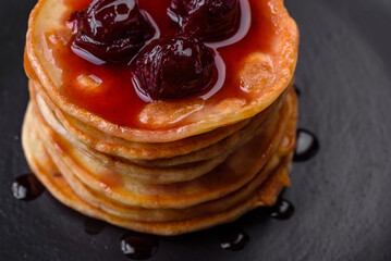 Delicious fresh pancakes with berry jam on a black ceramic plate