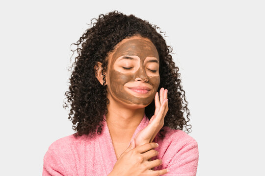 Young African American Curly Woman Wearing A Bathrobe And A Facial Mask Isolated