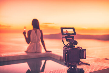 Videography behind the scene video camera shooting movie at sunset beach resort hotel filming actress woman acting, luxury travel. Professional videography equipment shooting outdoor at sunset. - 573033561