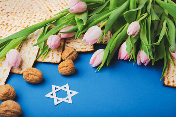 Passover Greeting Card with Mfatzah, Nuts and Pink Tulip Flowers on Blue Background.