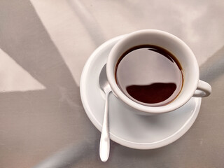 Top view of white mug with pyrex coffee and spoon on top of glass table