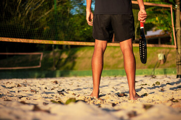 Man standing on beach tennis court with racket in hand