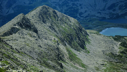 A rocky summit in Retezat mountains with rocky terrain, standing above Bucura glacier valley and lake. Summer in Carpathian Mountains. Romania. 