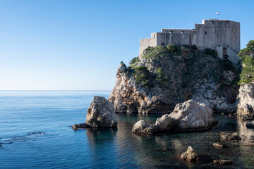 Beautiful Lovrinac fortress, on of many prominent Dubrovnik city medieval walls, rising above steep, sharp cliffs and blue Adriatic sea