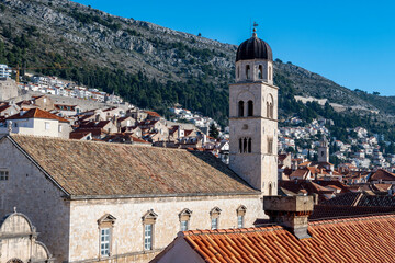 Obraz premium Franciscan Church and Monastery rising above Stradun street in amazing, fortified city of Dubrovnik, with rows of houses on the steep slopes in the background
