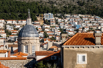 Fototapeta na wymiar Beautiful church tower of the Cathedral of the Assumption of the Virgin Mary, rising above red rooftops of Dubrovnik city, Croatia