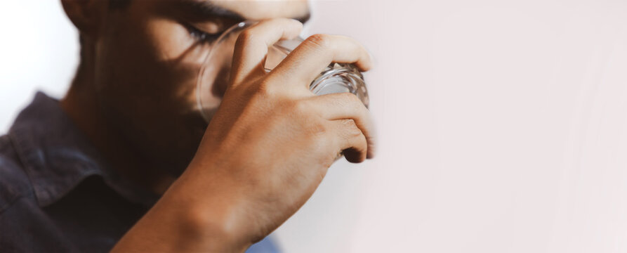 hombre joven triste y mirando con bebida en su mano en un fondo gris y espacio para texto, concepto de problemas con las bebidas alcoh&oacute;licas, depresi&oacute;n, alcoholismo. 