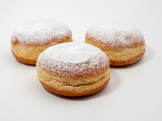 Freshly baked and dusted with powdered sugar German donuts. Donut berliner or krapfen on white background.