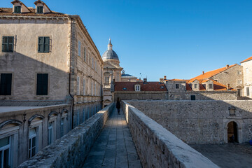 Fototapeta na wymiar Beautiful Dubrovnik city walk on old, medieval stone walls with view on the city rooftops and famous landmarks