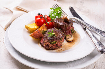 Traditional aged venison steak medallions with tomatoes, fries and mushrooms served as close-up on...