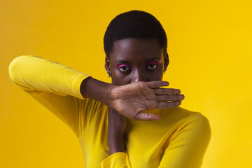 young beauty black woman cover mouth with hand isolated on yellow background