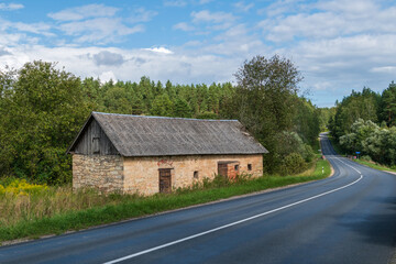 On the side of the road a stone house, a turn left and a white line