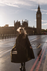 Tourism in London. Back view of traveler girl enjoying sight of Westminster palace and bridge on...