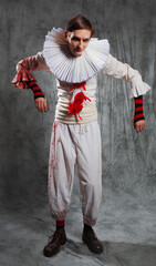 Sad clown from a horror movie, in a white suit with red pompoms and blood splashes