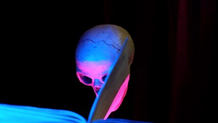 Skull and old open book. The wind turns the pages. Mystic and horror concept. Selective focus.