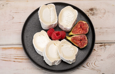 French organic matured white goat cheese with white rind close up served with fresh raspberries and figs
