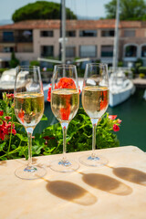 Drinking of French brut champagne sparkling wine in glasses in yacht harbour of Port Grimaud near Saint-Tropez, French Riviera vacation, France