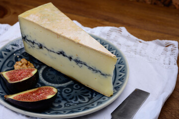 French semi-soft cow milk cheese morbier from Franche-Comte region with thin black layer and strong aroma close up