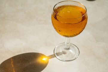 Drinking of French apple sparkling cider in glass on plastic table