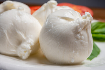 Eating of fresh handmade soft Italian cheese from Puglia, white balls of burrata or burratina cheese made from mozzarella and cream filling