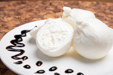 Eating of fresh handmade soft Italian cheese from Puglia, white balls of burrata or burratina cheese made from mozzarella and cream filling served with balsamico cream