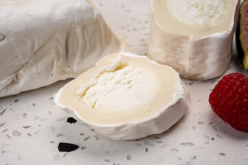 French organic matured white goat cheese with white rind close up served with fresh raspberries and figs