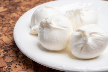 Eating of fresh handmade soft Italian cheese from Puglia, white balls of burrata or burratina cheese made from mozzarella and cream filling