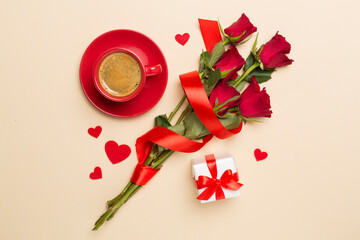 Red cup of coffee with roses on color background, top view