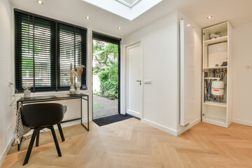 a home office with white walls and black shutters on the doors, wooden flooring and skylighted...