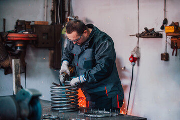 Locksmith in special clothes and goggles works in production. Metal processing with angle grinder. Sparks in metalworking.