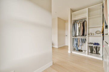 a walk - in closet with clothes hanging on the wall, and an open door that leads to another room