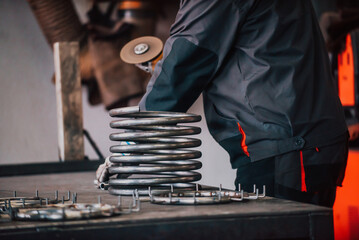 Locksmith in special clothes and goggles works in production. Metal processing with angle grinder. Sparks in metalworking.