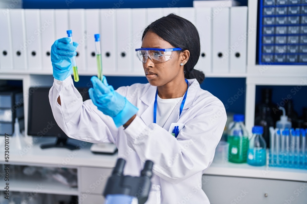 Canvas Prints Young african american woman scientist holding test tubes at laboratory