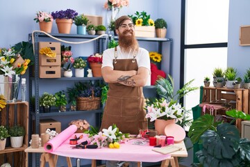 Young redhead man florist smiling confident standing with arms crossed gesture at flower shop