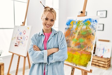 Young caucasian woman artist smiling confident standing with arms crossed gesture at art studio