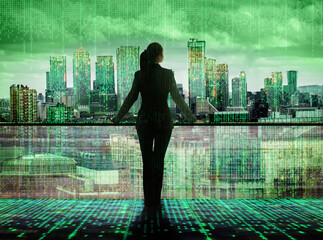 Businesswoman looking over the matrix  concept City of London. Virtual connectivity of the city. Financial district skyline with matrix background in green.
